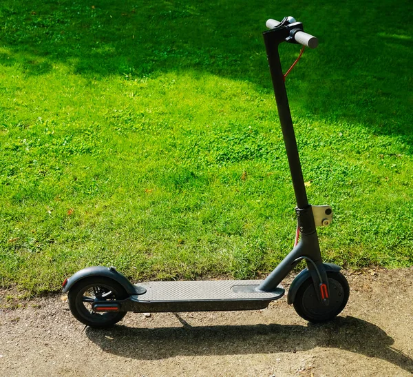 Yeşil çimen arka planında yeni bir elektrikli scooter. Yaz parkı. 