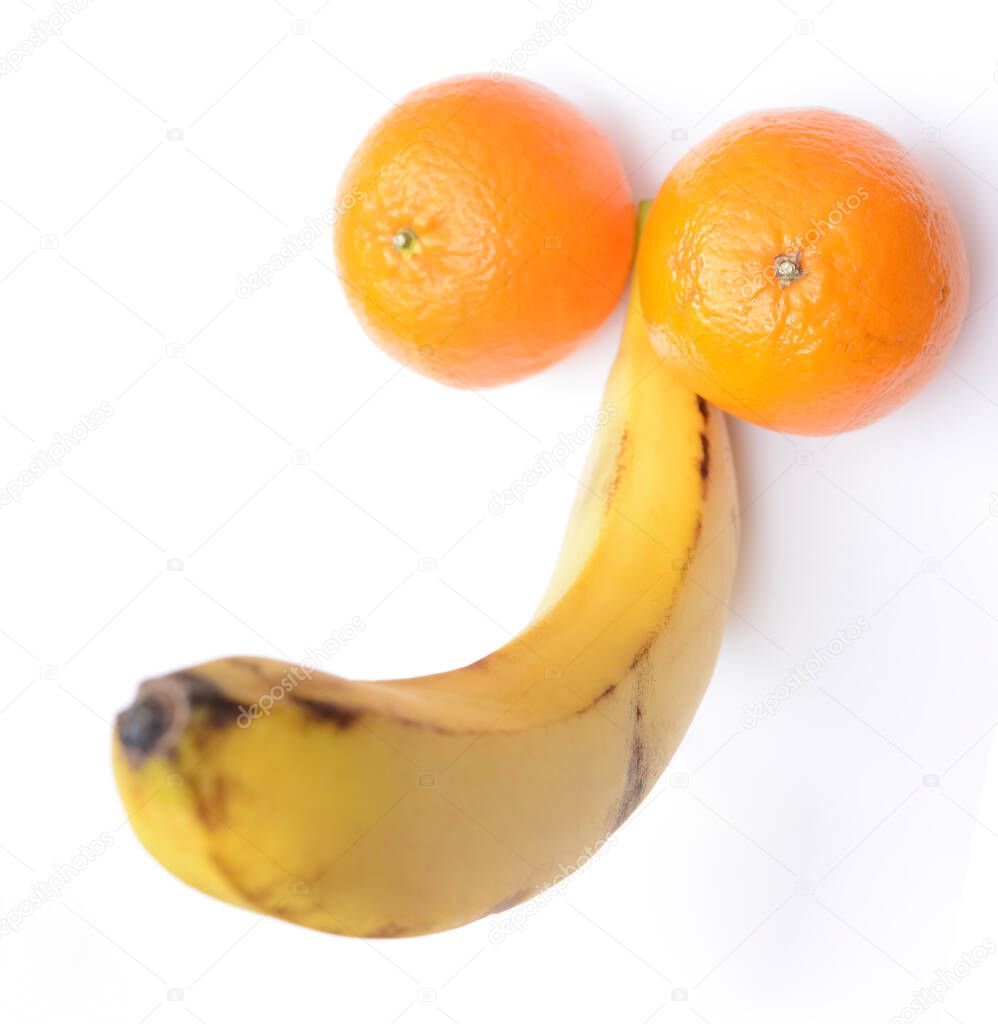 A flat lay of ripe banana and two fresh mandarines represent a penis concept. isolated on white background. male genitals