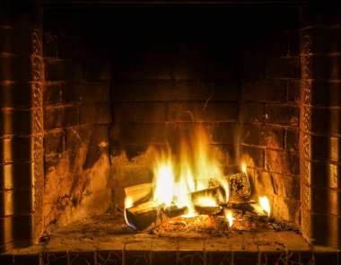 Şöminede yangın var. Şöminede odun odunlarıyla yanan alevler. Sıcak sahne, sarı ve turuncu fişeklerle.