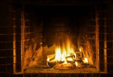 Şöminede yangın var. Şöminede odun odunlarıyla yanan alevler. Sıcak sahne, sarı ve turuncu fişeklerle.