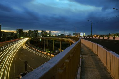 Şehirdeki çelik bir köprünün altında geceleri trafik ışıklarının hızına uzun süre maruz kalmak. Chelyabinsk, Rusya.