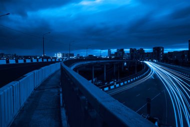 Şehirdeki çelik bir köprünün altında geceleri trafik ışıklarının hızına uzun süre maruz kalmak. Chelyabinsk, Rusya.