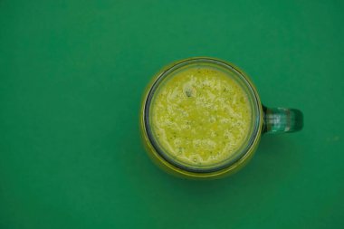 Dolu cam kavanoz, yeşil arka planda izole edilmiş kulplu bardak. Yazı için smoothie boş kopya alanı. en üstteki görünüm