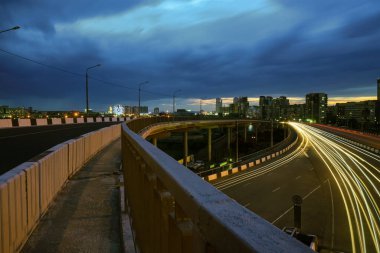 Şehirdeki çelik bir köprünün altında geceleri trafik ışıklarının hızına uzun süre maruz kalmak. Chelyabinsk, Rusya.