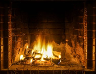 Şöminede yangın var. Şöminede odun odunlarıyla yanan alevler. Sıcak sahne, sarı ve turuncu fişeklerle.