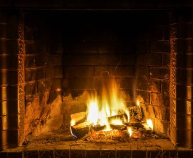 Şöminede yangın var. Şöminede odun odunlarıyla yanan alevler. Sıcak sahne, sarı ve turuncu fişeklerle.