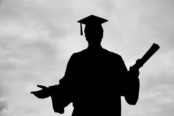 silhouette of  graduated student man in cap gown showing  diploma scroll isolated on white  background. Celebrating graduation ceremony concept