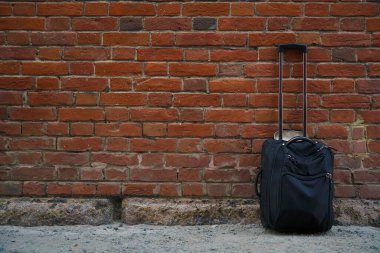 Kırmızı tuğlalı arka planda bavullar. Yazı için boş kopyalama alanı.