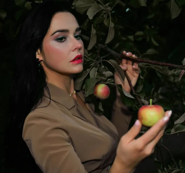 红色和绿色的苹果在女性手中 穿着秋装的女人站在苹果树下看着苹果 妇女健康 生殖生产 — 图库照片