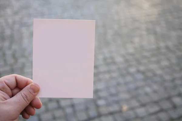 Mão Masculina Segurando Cartão Branco Fundo Paralelepípedo Cinza Espaço Cópia — Fotografia de Stock