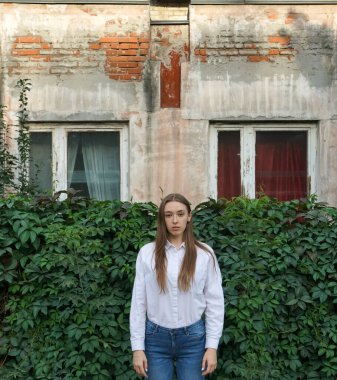 Sarmaşık 'ta iki pencereli beyaz gömlekli genç bir kadın. Sonbahar ya da Yaz mevsimi. 