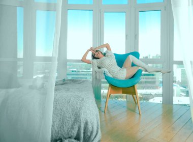 Genç sarışın kadın modern sandalyede oturuyor..