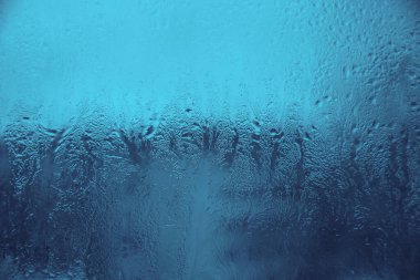 Camdaki desenler, kışın camdaki donuk çizimler, mavi arka plan ve buz çizimleri, damlacıklar. Camdan yansıma