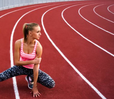 Bacağını esneten kaslı sarışın kadın. Spor. Kaçak. Stadyumda koşmadan önce esneyen sporcu kadın.
