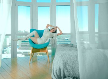 Genç sarışın kadın modern sandalyede oturuyor..