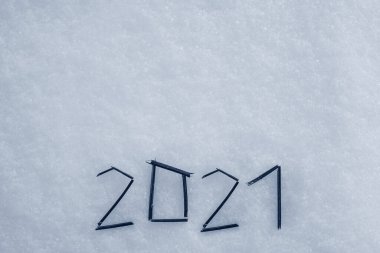 Düz kar yüzeyindeki çubuklardan yapılmış 2021 metin mektubu. Yılbaşı Noel kartpostalı, tebrik kartı..