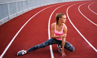 Bacağını esneten kaslı sarışın kadın. Spor. Kaçak. Stadyumda koşmadan önce esneyen sporcu kadın.