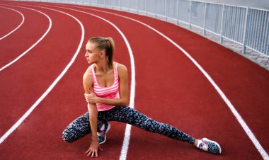 Bacağını esneten kaslı sarışın kadın. Spor. Kaçak. Stadyumda koşmadan önce esneyen sporcu kadın.