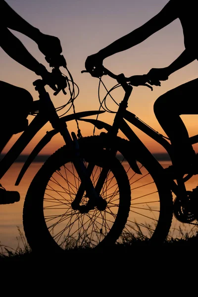 2人の自転車が向かい合って立っています 日没のビーチを背景に — ストック写真