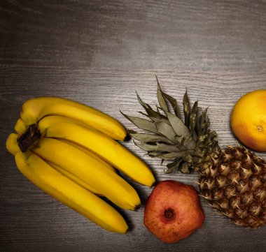  Bir ananas, greyfurt, nar ve taze muz. Üst Manzara. Siyah ahşap masa arka planı. Boş kopya alanı. sıra sağlıklı yiyecekler
