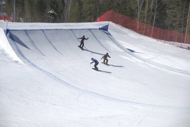 Snowboardcu bir kar parkında ormana karşı sıçrama tahtasından atlıyor. spor ögesi