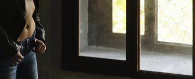  Siyah deri ceket ve kot giyen bir kadın. Pencerenin yanında duran kadın. Gün ışığı. Yüzü yok.
