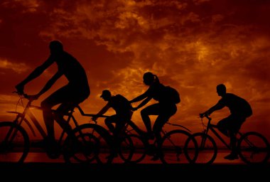 Boşluk. Gün batımında bisiklete binen sportif arkadaşlar. Bisikletçiler sahil boyunca gidiyor. Doğa arka planında spor.