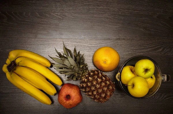 Pineapple, bananas and yellow apples on black wooden background. Tropical fruit.  ingredients for smoothie