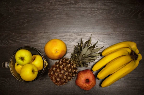 Pineapple, bananas and yellow apples on black wooden background. Tropical fruit.  ingredients for smoothie