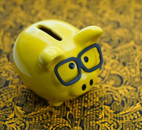 yellow piggy bank with glasses  on paper background.