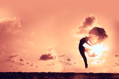 Gün batımının önünde dans eden bir balerin silueti.