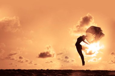 Gün batımının önünde dans eden bir balerin silueti.