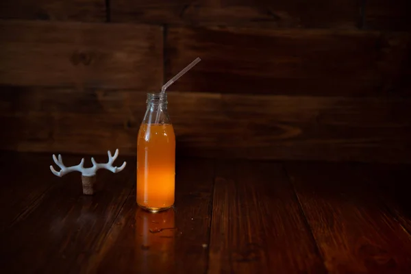 Una botella vintage de jugo recién exprimido sobre un fondo de madera y un ampersand brillante. Cerca de corcho de vino decorado con astas de ciervo — Foto de Stock
