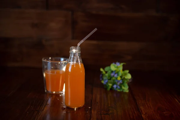 Botol vintage dengan jus, jerami dan bunga di atas meja kayu — Stok Foto