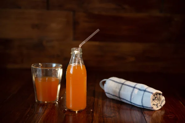 Botol vintage dengan jus, jerami dan handuk di atas meja kayu — Stok Foto