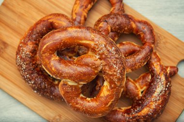 Taze pişmiş ev yapımı yumuşak pretzel ahşap kesme tahtası üzerinde tuz ile