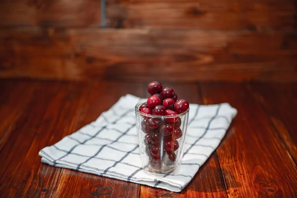 Sweet cherry, black cherries in a glass on wooden background