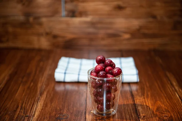 Sweet cherry, black cherries in a glass on wooden background