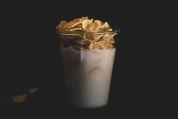 Jagung serpih dengan susu dalam gelas terisolasi pada hitam — Stok Foto