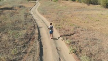 adam güneş tarafından yanmış bozkır yolda yürüyor