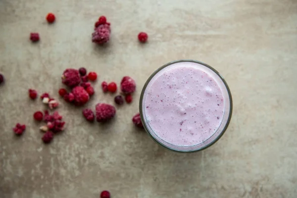 Tata letak kreatif terbuat dari raspberry, strawberry dan smoothie kelapa. Konsep makanan. Smoothie pada latar belakang abu-abu . Stok Gambar