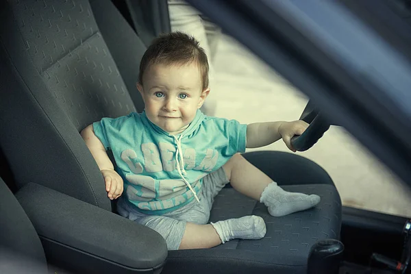 one and a half year old child sits behind the wheel of a car