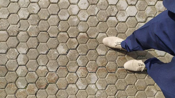 Pedras de pavimentação molhadas com duas pernas em sapatos cinza . — Fotografia de Stock