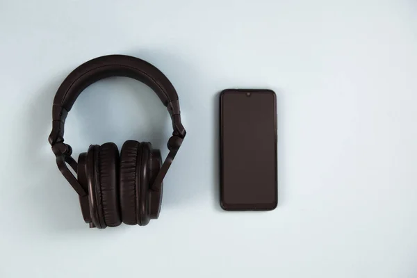 Wireless headphones with smartphone on white background