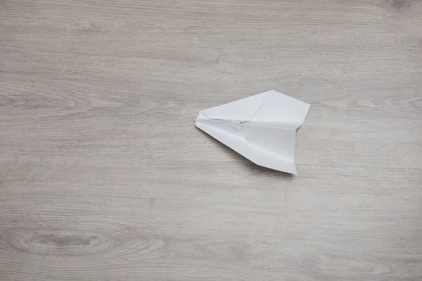 Як зробити орігамі паперовий літак покрокова інструкція по фото на дерев'яному столі з руками. Крок 12 — стокове фото
