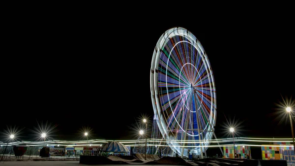 Longa exposição da roda gigante iluminada à noite com espaço de cópia — Fotografia de Stock