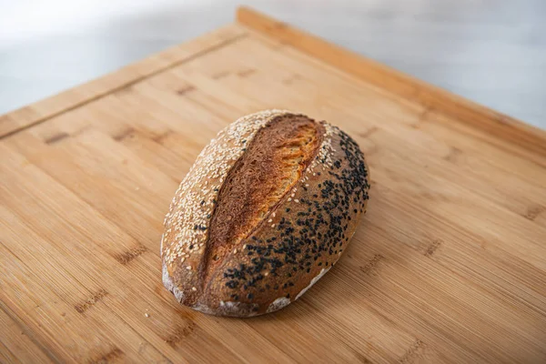 Řemeslný chléb je posypaný bílými a černými sezamovými semínky na dřevěném pozadí s kopírovacím prostorem — Stock fotografie