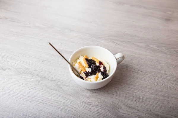 Helado de vainilla con mermelada de mora en una taza blanca sobre un fondo claro de madera — Foto de Stock
