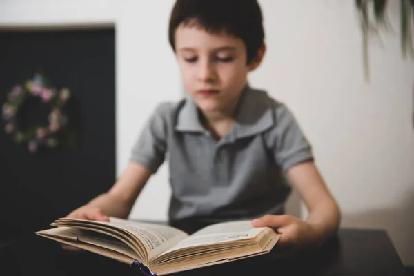 Imagem vaga de um menino lendo um livro — Fotografia de Stock