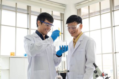 Bilim, Kimya, Teknoloji, Biyoloji ve Laboratuar Konsepti - Asyalı kıdemli bilim adamı ve Asyalı kıdemsiz bilim adamları deney sonuçları için mutluluk ve gülümseme.